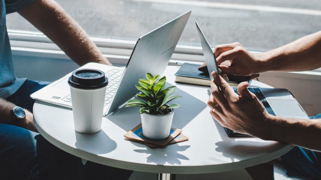 2 people sitting at table using laptops