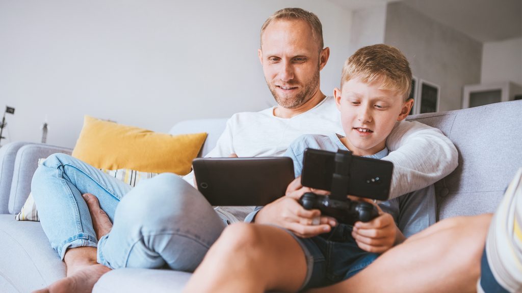 son and father with phones on couch